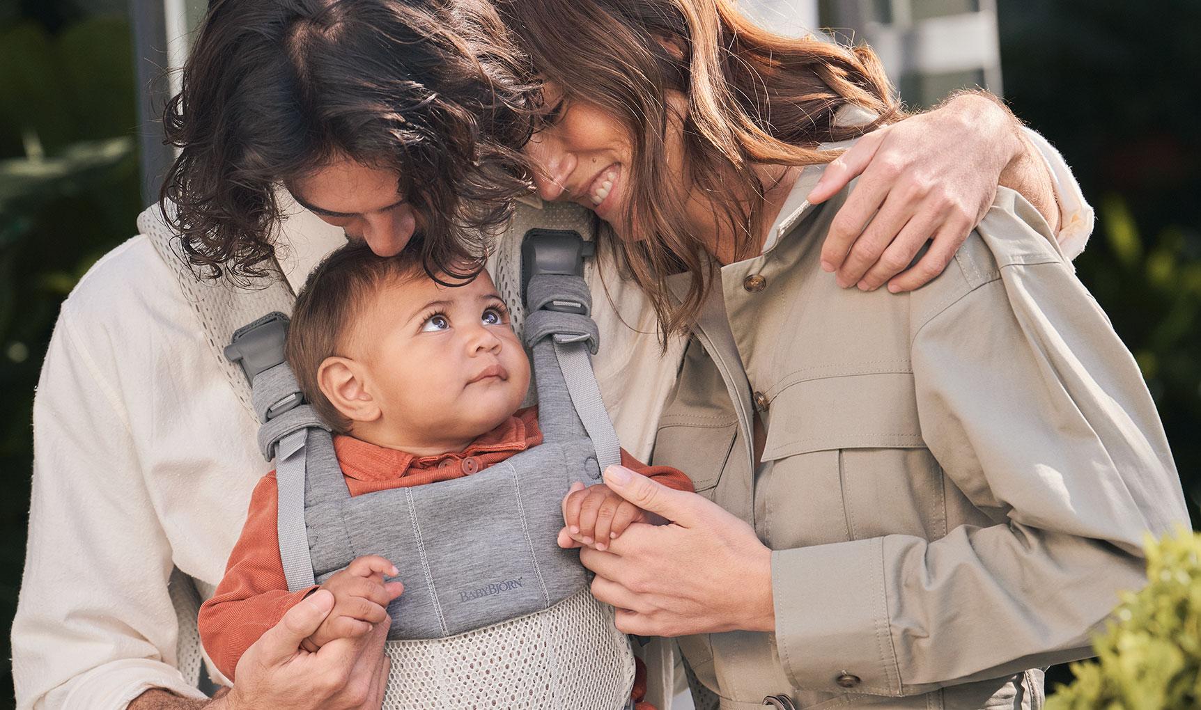 mother and father with baby in a baby carrier